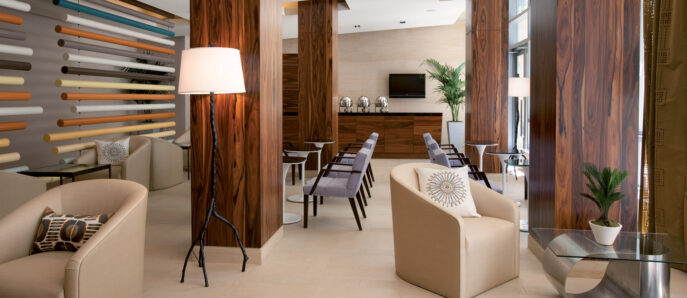 Spacious contemporary dining room featuring rich walnut wood paneling, sleek beige stone floors, and modern furnishings. Vertical wine storage adds an artistic focal point, while warm lighting enhances the cozy, yet elegant ambiance.