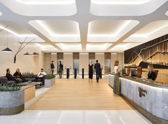 A modern and sleek office lobby with people engaged in various activities, featuring geometric lighting fixtures, wood paneling, and a stylish reception desk.