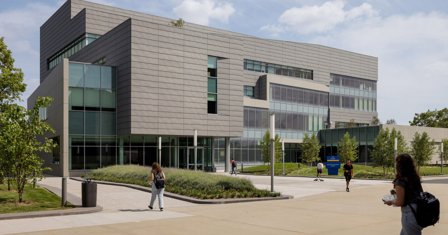 Modern educational building featuring clean lines, expansive glass facade for natural lighting, and aluminum composite panels. Landscaped with young trees and pedestrian pathways, the design encourages student engagement and environmental harmony.