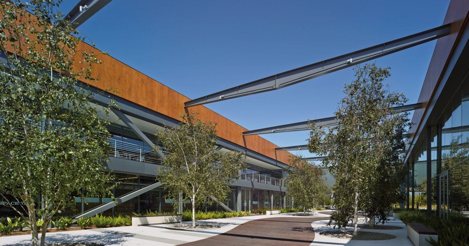 Modern office park with connecting walkways amid landscaped greenery on a bright sunny day.