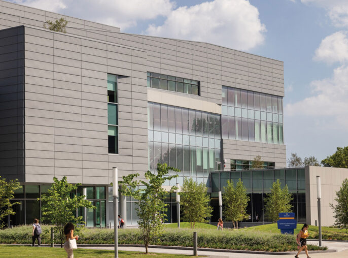 Modern educational building featuring clean lines, expansive glass facade for natural lighting, and aluminum composite panels. Landscaped with young trees and pedestrian pathways, the design encourages student engagement and environmental harmony.