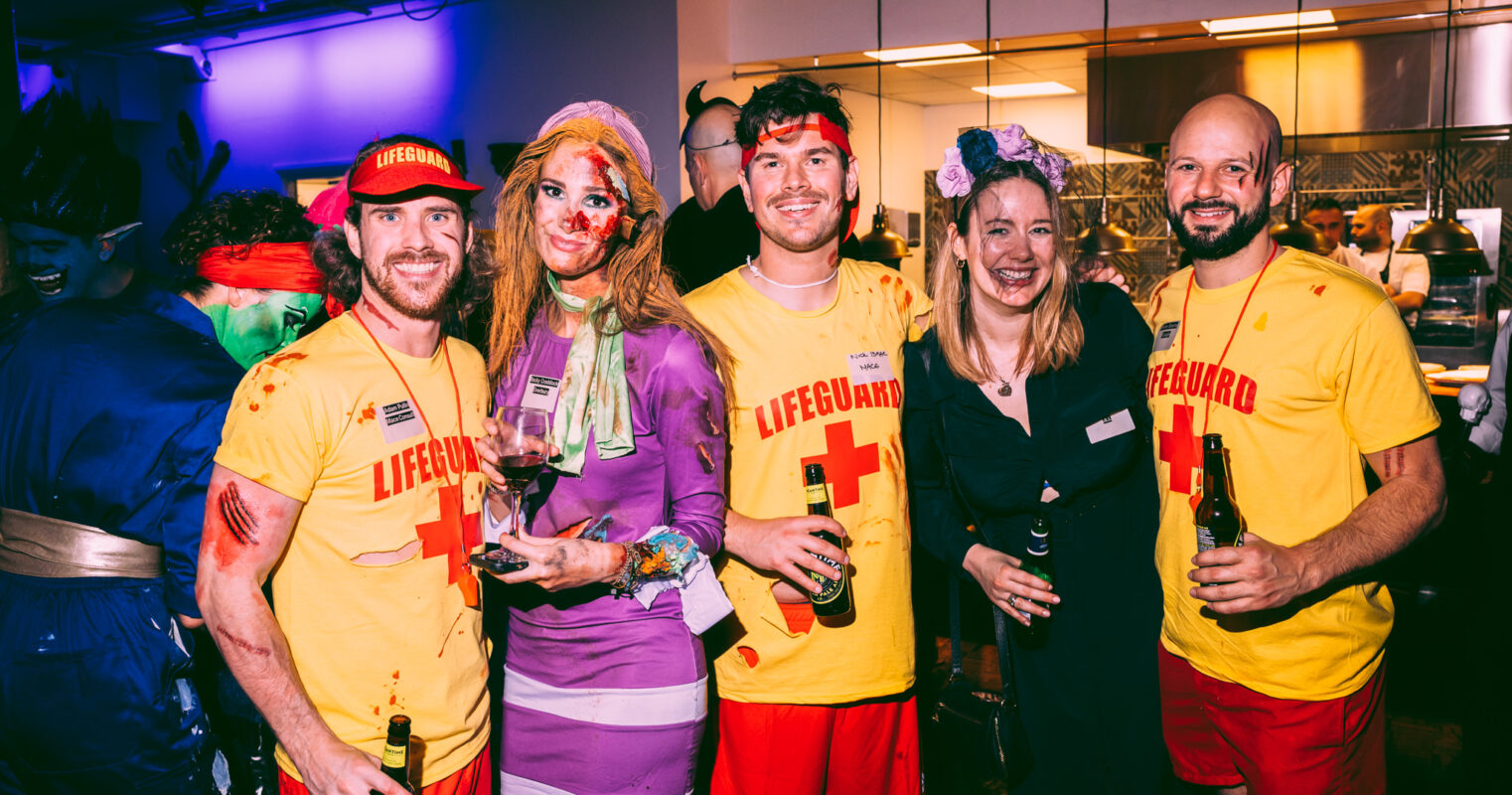 A group in lifeguard-themed costumes adds a humorous twist to the party atmosphere.