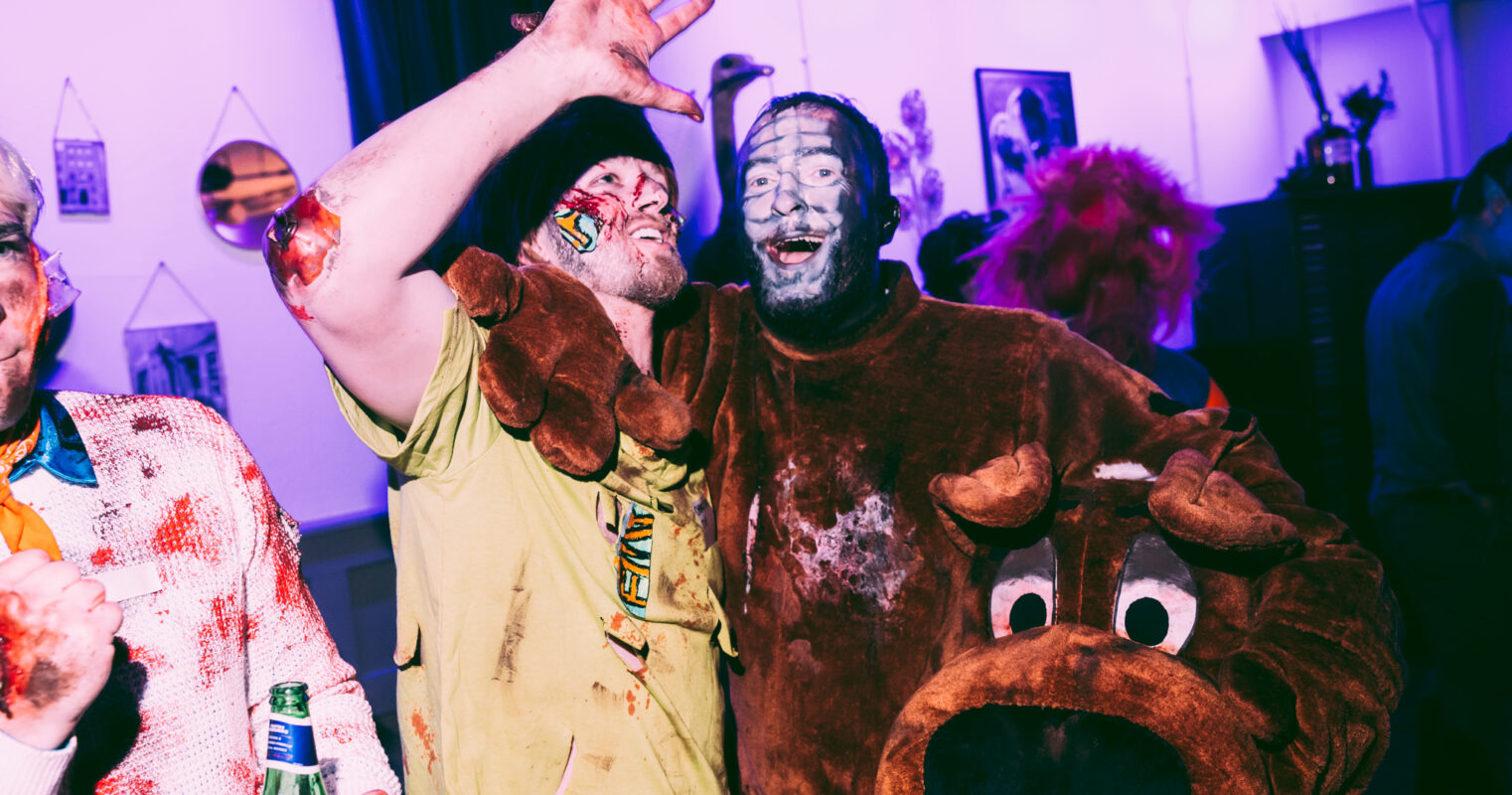 Two people in zombie and mascot costumes posing playfully, adding a comical touch to a gory theme.