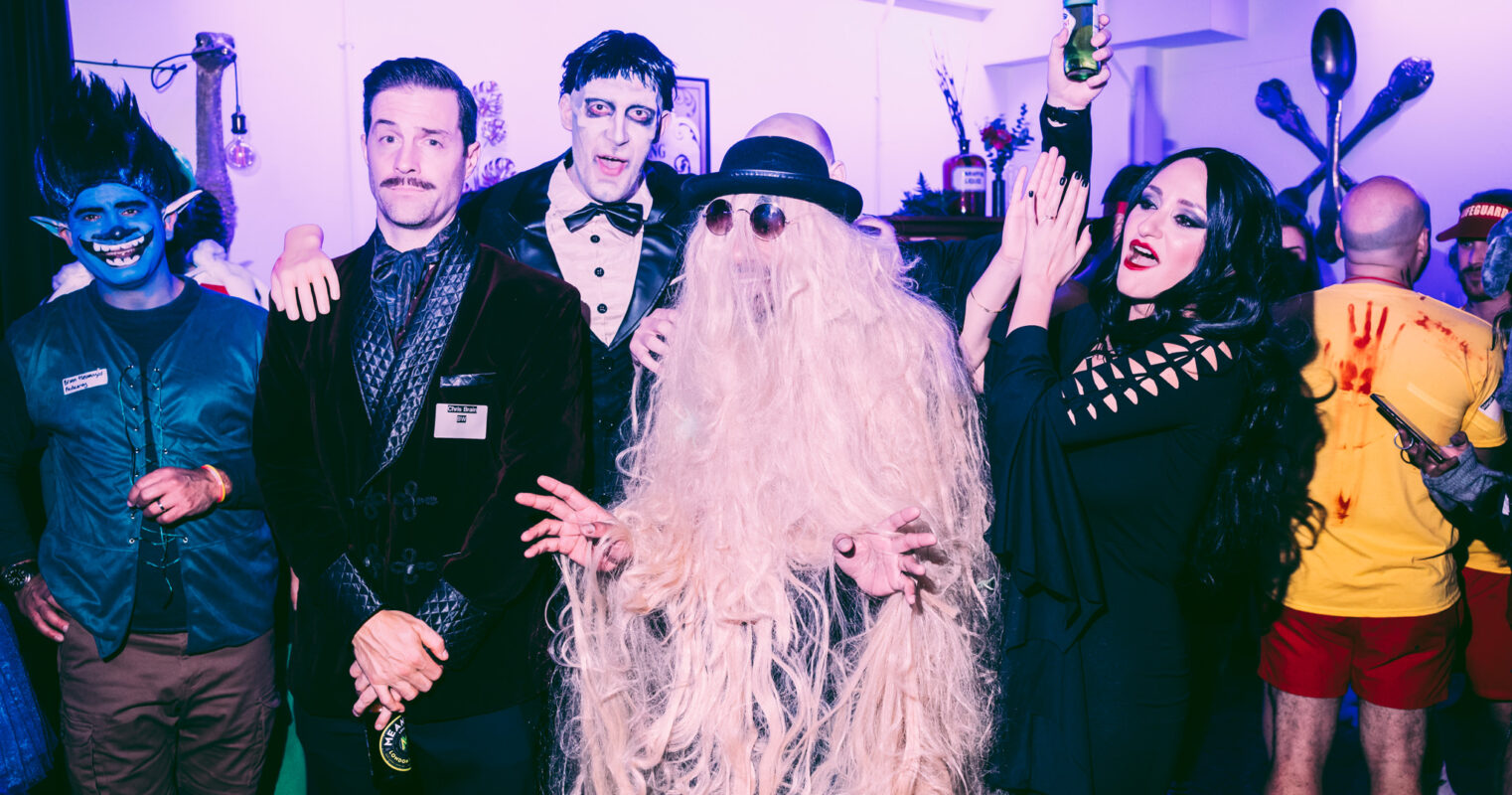 A colorful costume party with individuals dressed as mythical and horror characters, capturing a festive and humorous atmosphere.