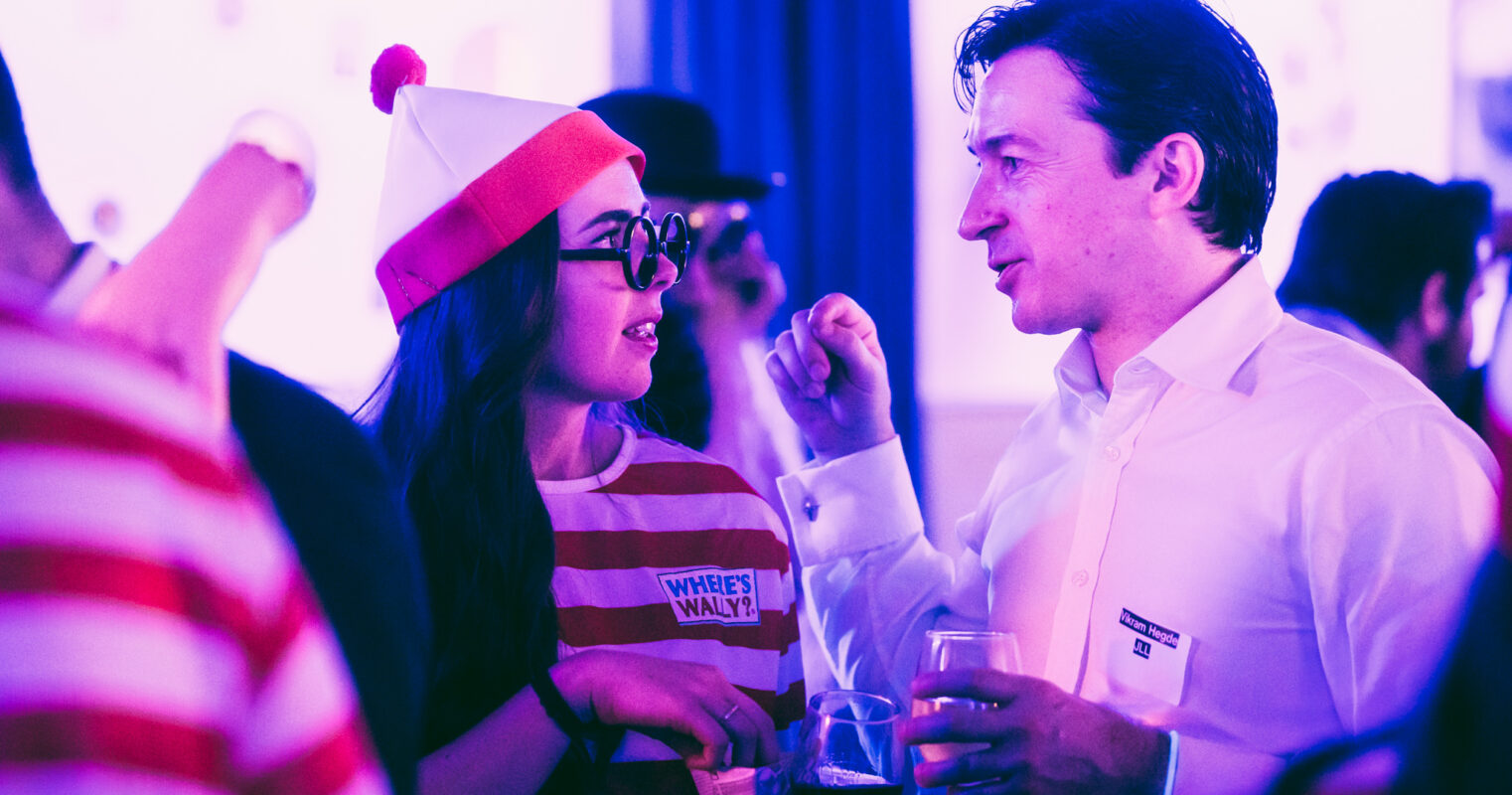 Two party-goers in 'Where's Wally' costumes share a conversation, adding a whimsical touch.