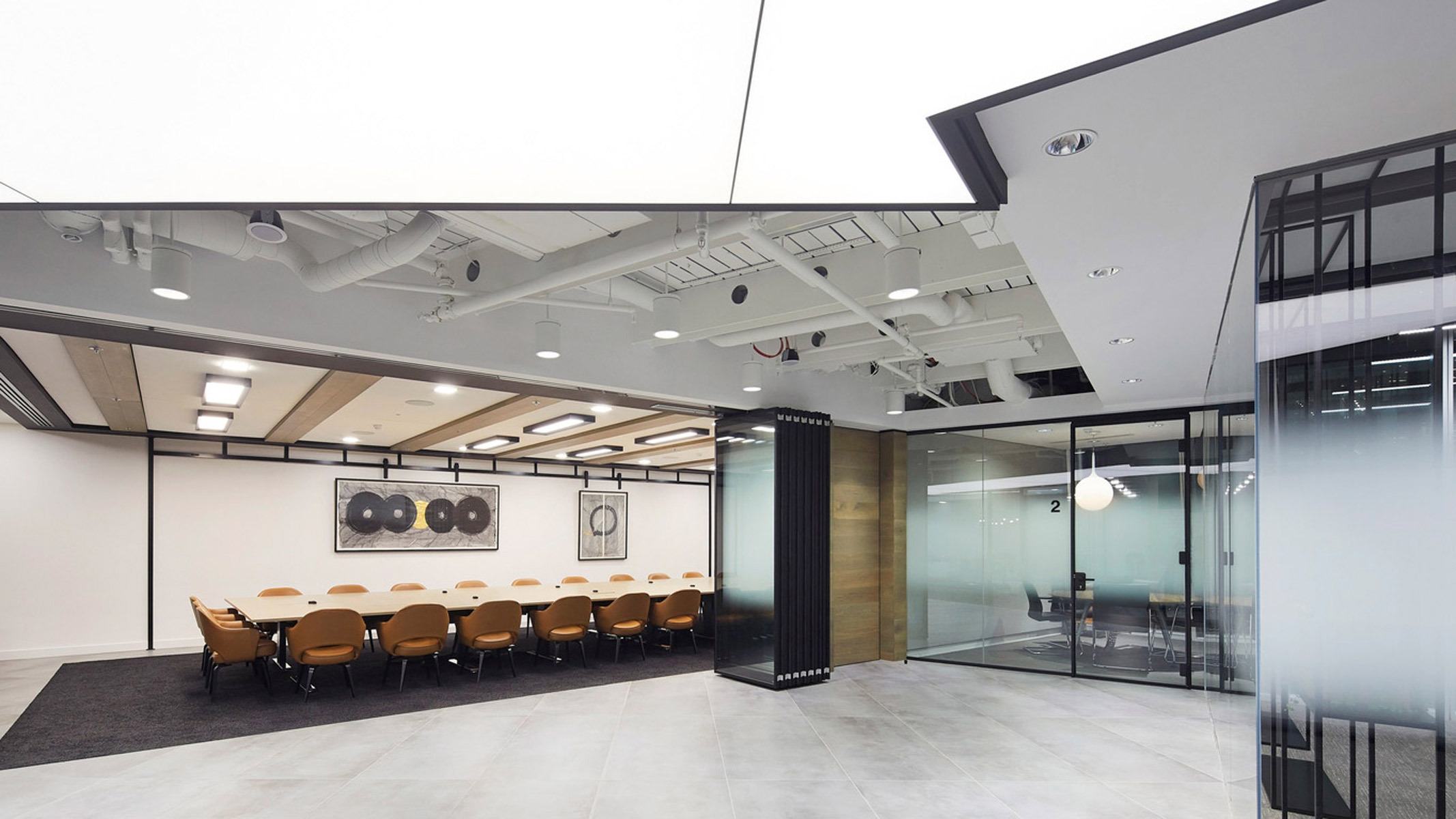Modern conference room boasting a sleek, monochrome color palette with contrastive brown chairs and strategic lighting; features exposed ductwork, a reflective whiteboard, and glass partitions fostering a sense of openness while maintaining distinct functional areas.